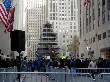 Construction of Rockefeller Centre Christmas Tree and crowds outside NBC Studios<br>Location: <a href="https://www.google.com/maps/search/?api=1&query=40.75795,-73.97933" target="_new">Rockefeller Plaza</a>
